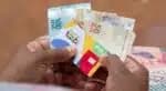 Cidadã com cartão do Bolsa Familia e dinheiro em mãos (Foto: Reprodução/ Internet)